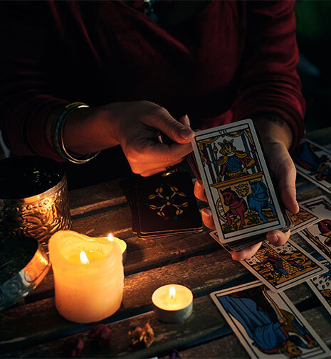 A woman displays a tarot card, illuminated by the soft glow of candles, suggesting a moment of reflection and insight.
